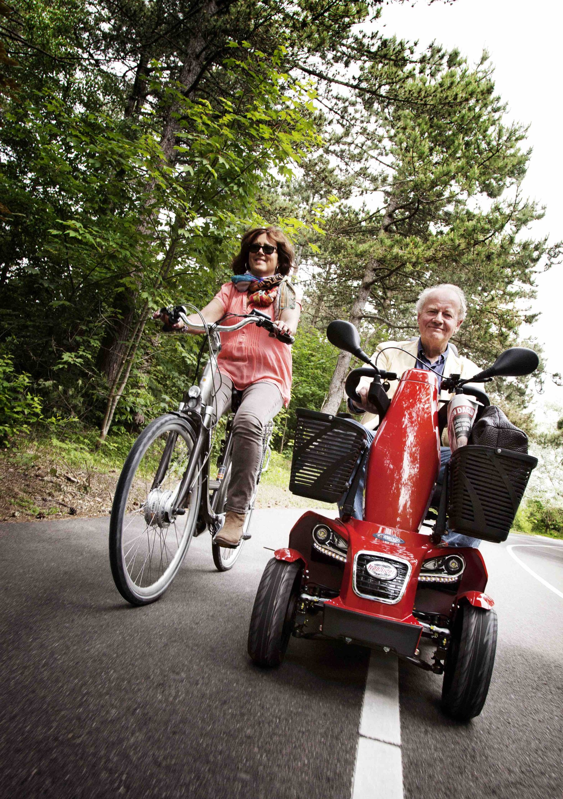 Two people enjoying the outdoors — one on a bicycle, one on a Mango mobility scooter
