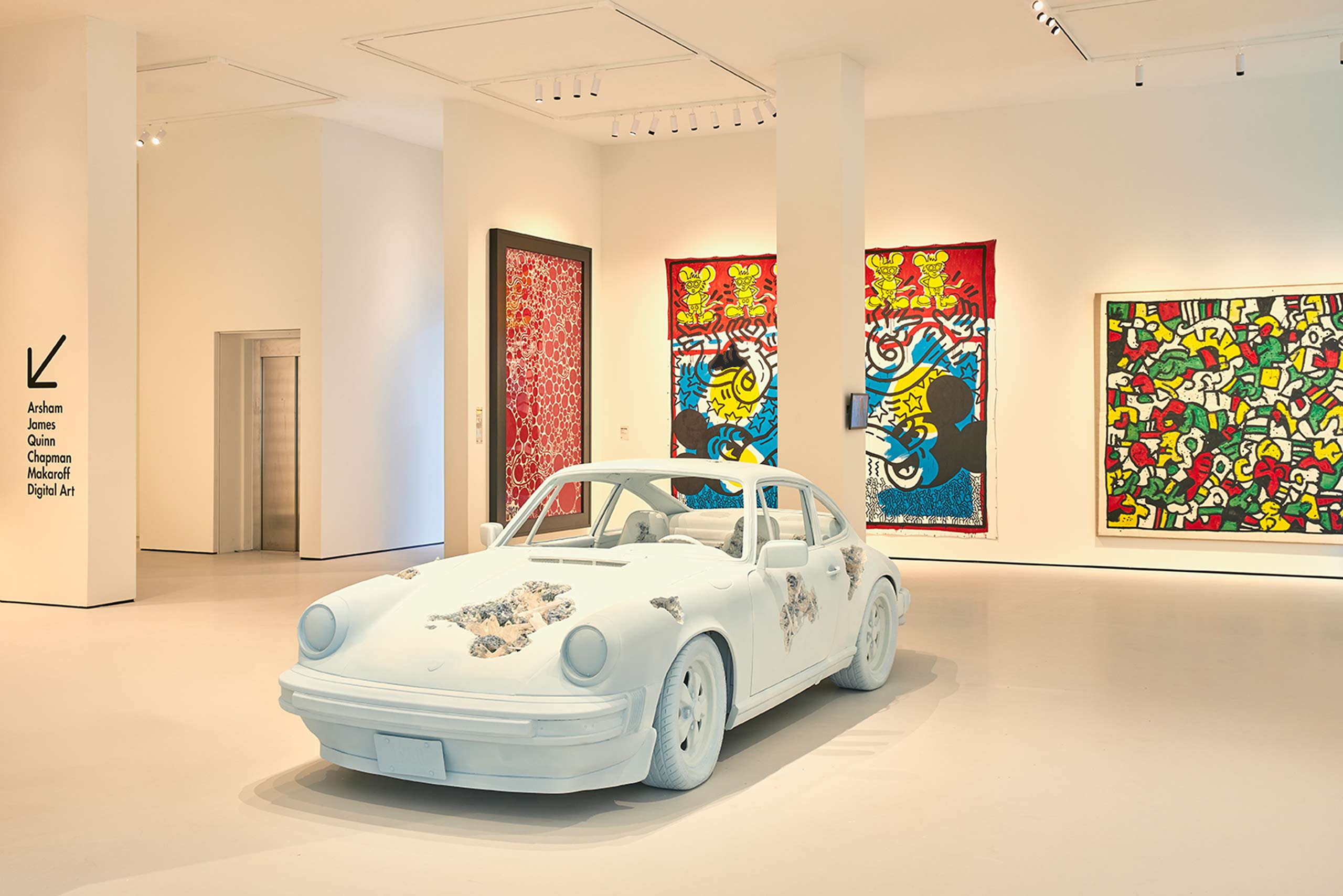 Moco Museum gallery with Keith Haring artworks and an Arsham eroded Porsche sculpture